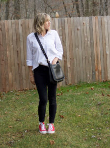 woman wearing chuck taylor all star sneakers with jeans and a blouse