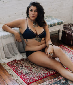 Cheyenne Gil, body positive boudoir photographer, posing in her studio.